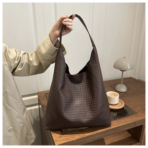 Détail de la texture en cuir tressé marron foncé et de la bandoulière large du cabas