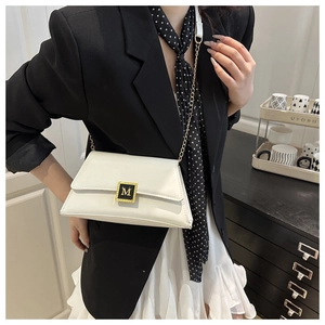 Detailed view of a white leather pillow bag with gold M-buckle on a female model