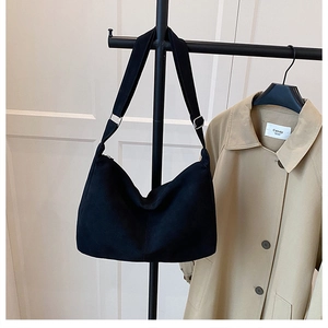 Detail of minimalist black tote bag with textured fabric and adjustable strap buckles