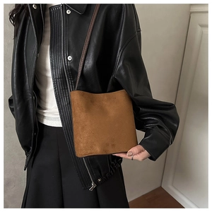 Close-up of caramel brown suede crossbody bag styled with a black leather jacket