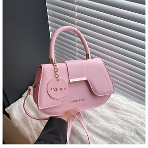 Close-up of pink faux leather saddle bag with golden bar buckle and fashion pendant