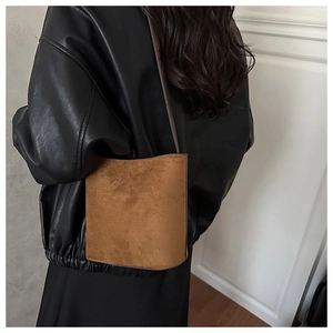 Sac seau en cuir nubuck marron porté à l'épaule montrant la taille et la texture mate