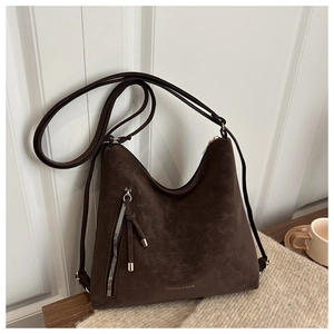 Gros plan du sac fourre-tout marron mat en daim avec fermeture éclair et logo doré