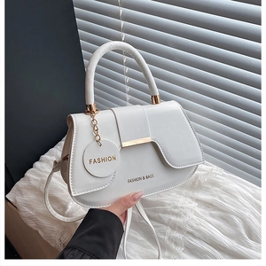 Detail of white saddle bag with golden hardware and fashion letter circular pendant