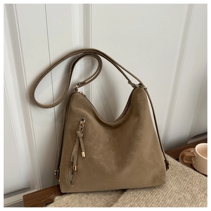 Détail macro du sac hobo en cuir marron mat avec fermeture éclair dorée et sangle
