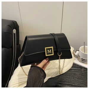 Close-up of elegant black leather pillow bag with gold M-buckle and chain strap