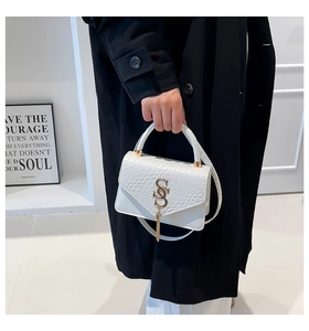 Detail of white snakeskin texture bag with gold S-logo and stylish tassel decor