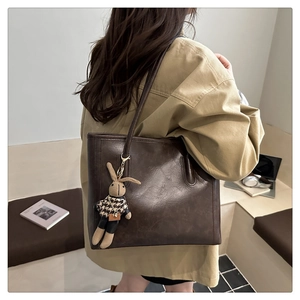 Detail of dark brown tote bag with premium faux leather texture and knit rabbit charm