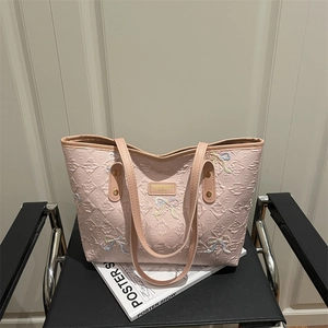 Pink quilted tote bag featuring colorful embroidered bows and long leather handles