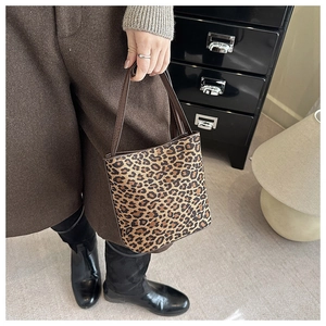 Detail of leopard print bucket bag featuring brown leather handles and fuzzy texture