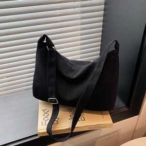 Minimalist black canvas tote bag with adjustable strap shown in a natural window setting