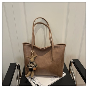 Detailed view of a brown vintage tote bag with a cute rabbit pendant on a magazine