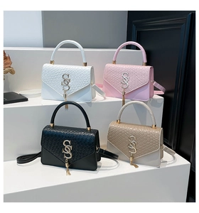 Detail of elegant handbags with crocodile texture, fringe tassels and golden SS logo accents