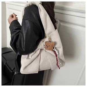 Detail of corduroy tote bag featuring a large bow and cute teddy bear pendant charm