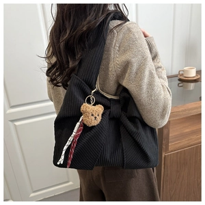 Detail of black corduroy tote bag featuring a bow design and a cute teddy bear charm