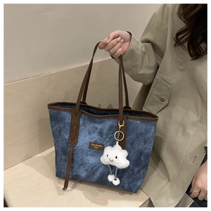 Detail of blue marble-textured tote bag with leather handles and cloud charm accessory