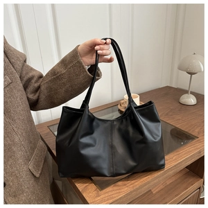 Detail einer großen schwarzen Totebag aus weichem Leder mit vertikaler Naht und Schultergurten