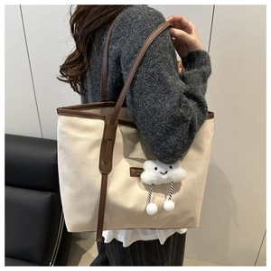 Detail of canvas tote bag with brown leather trim and cute plush cloud keychain charm