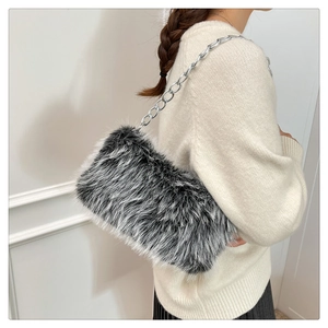 Detail of faux fur shoulder bag with silver chain strap on a model wearing a beige sweater