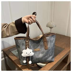 Close-up of retro tote bag with grey texture, leather trim and cute cloud charm