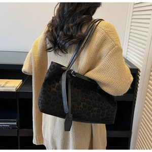 Detail of dark leopard print shoulder bag with leather strap on beige knit sweater
