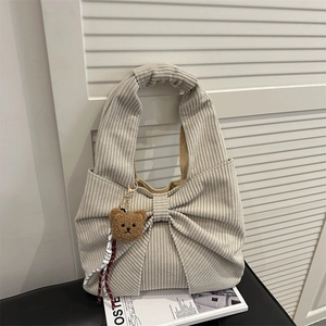 Beige corduroy shoulder bag with large bow design and plush bear charm for autumn style