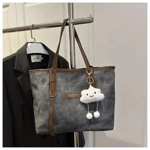 Detail of vintage tote bag with gold logo, contrast trim and plush cloud charm