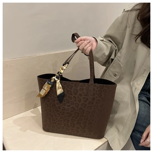 Detail of a large brown leopard print suede tote bag decorated with a silk scarf