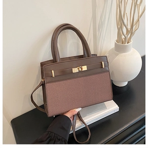 Detail of color-block handbag showing brown textured leather and golden flip lock