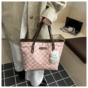 Detail of pink plaid tote bag with brown leather handles and a cute bear charm