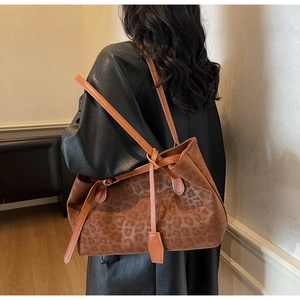 Detail view of large leopard print tote bag with orange straps and knot decor