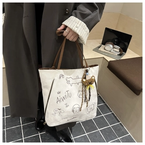 Detail of white canvas tote with cartoon illustrations and brown plush bear charm