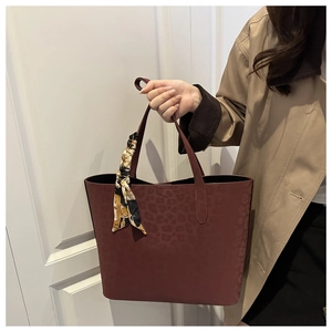 Detail of burgundy leopard embossed tote bag with black scarf and khaki trench coat