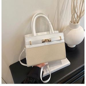 Detail of a two-tone leather and woven handbag with a gold twist-lock on a modern book