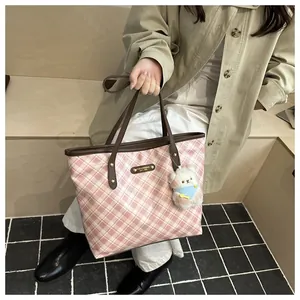 Pink plaid tote bag detail with golden metal logo and white plush bear charm