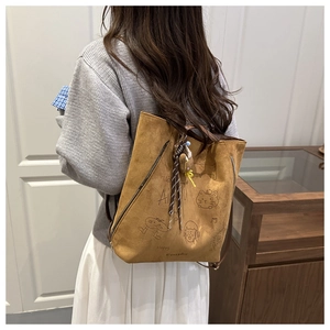 Rear view of model wearing a brown suede backpack with cute hand-drawn cat illustrations