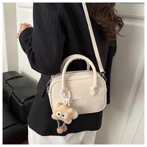 Detail van beige Boston-tas met matte textuur en zachte pluche sterrenhanger