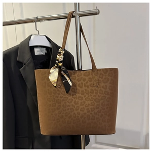 Detail of leopard print tote bag featuring a decorative floral scarf on the leather handle