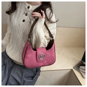 Detail of pink hobo bag with metallic M logo and adjustable leather strap worn by model