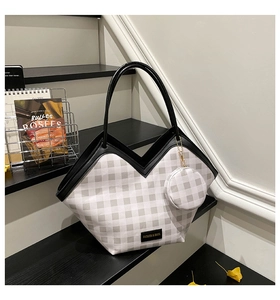 Detail of checkered tote bag with V-shaped leather trim and round coin purse on stairs