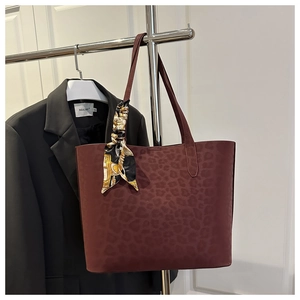 Detail of burgundy leopard embossed tote bag with vintage printed silk scarf on handle