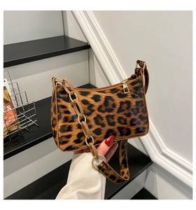 Detail of leopard print baguette bag with golden zipper and chunky acrylic chain strap