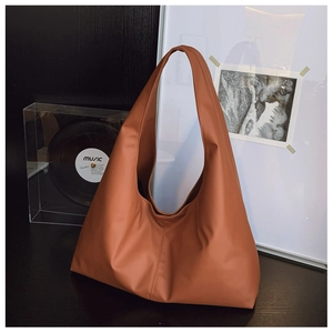 Minimalist caramel faux leather tote bag on black wooden surface with vintage record player