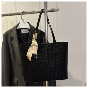 Detail view of large leopard print tote bag with decorative silk scarf hanging on a hanger