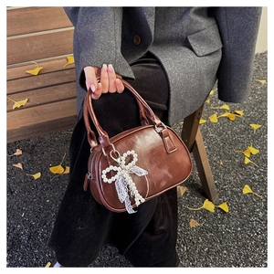 Detail of a brown vintage bowling bag with a pearl bow charm and elegant lace lining