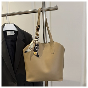 Close-up of khaki tote bag with elegant black-gold floral silk scarf on metal hanger