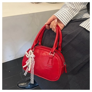 Close-up of red PU bowling bag with elegant white lace bow and pearl charm detail