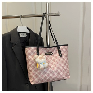 Detailed view of pink plaid tote bag with metal nameplate and plush animal charm decoration