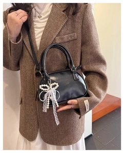 Detail of black mini handbag with pearl bow charm and white lace on wool blazer