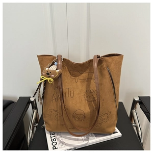 Detail of brown suede tote bag with dog embroidery, bear pendant and side zipper